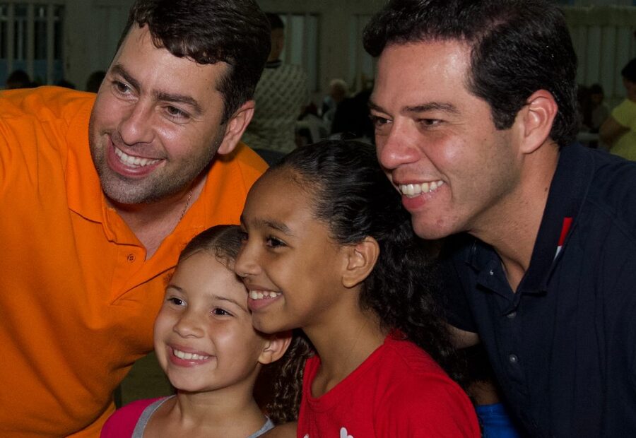 Túlio Arruda ao lado de duas crianças sorrindo