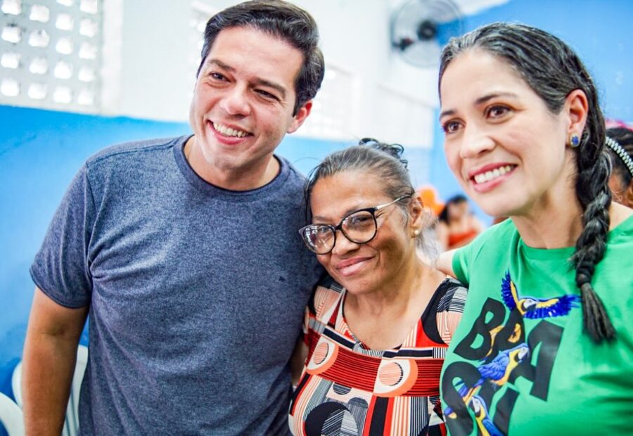 Túlio Arruda sorrindo ao lado de duas moradoras